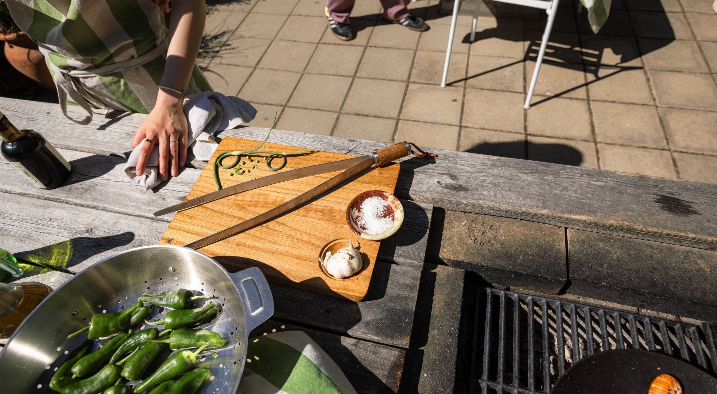 Grillzange mit Gravur auf einem Holz Schneidebrett in der Outdoorküche.